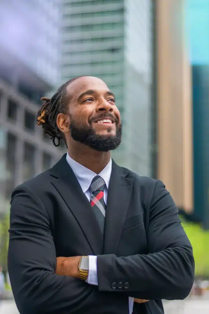 Black male business person with arms crossed, outside smiling