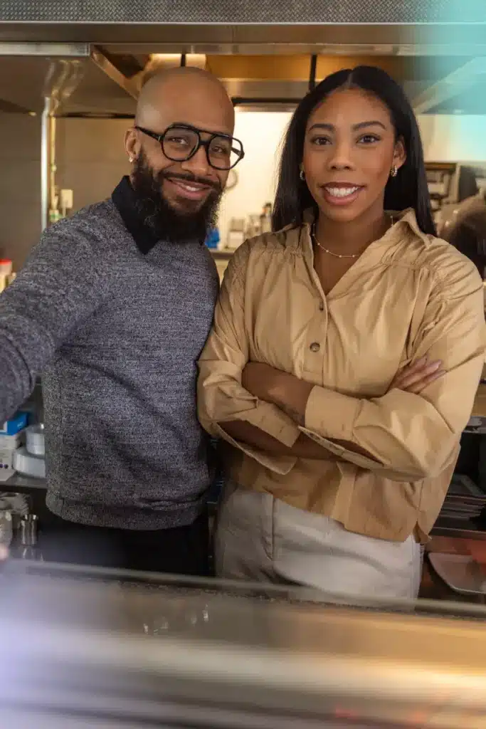 Black couple behind a counter. Looks like business owners
