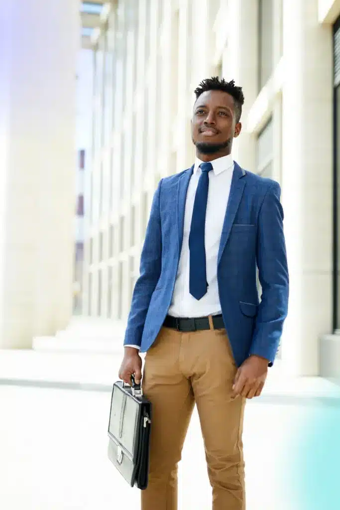 Black male entrepreneur with a briefcase outside of a building, smiling